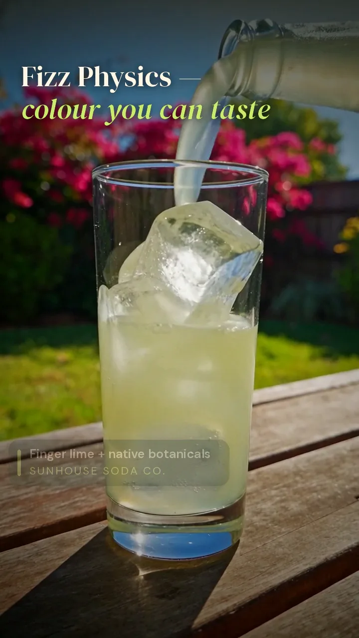 A glass of pale-green soda being poured in a sunny backyard