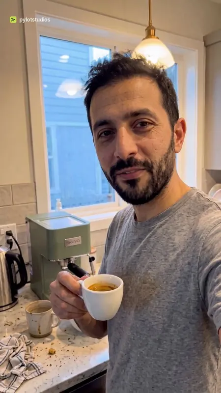 A presenter in his kitchen holding a fresh espresso beside a Bruvo machine, poster frame from the Bruvo coffee machine sample advert
