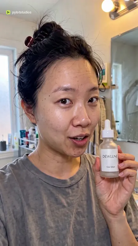 A presenter holding a Dewlune serum dropper bottle up to the camera, poster frame from the Dewlune serum sample advert
